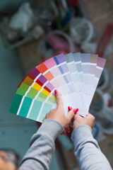 Close-up of a female designer choosing paint samples for walls. A girl looks at a color sample to...