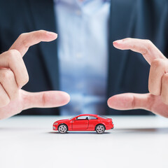 Businessman hand cover or protection red car toy on table. Car insurance, warranty, repair, Financial, banking and money concept
