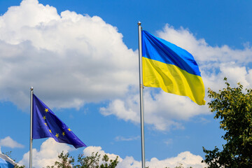 Waving flag of European Union and flag of Ukraine against blue sky