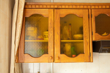 Old brown wooden kitchen cabinet with glass doors in the kitchen at home, kitchen furniture