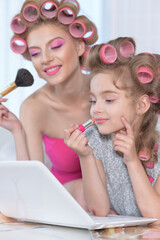 Mother and little daughter with laptop applying  make up