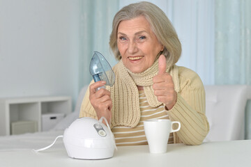 Senior woman sitting  with inhaler showing thumb up