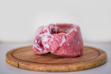 Frozen pork meat on a cutting board.