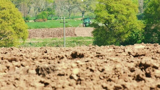 Low angle. A farmer driving a tractor moves toward the camera , Cornwall, England, UK.