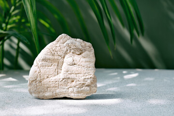 White stone as podiums display before deep green surface and palm leaves for product presentation....
