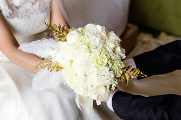 Obraz na płótnie Canvas Groom and bride holding white bouquet together