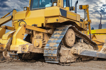Bulldozer machine is leveling construction site. Earthmover with sky background. close-up. construction heavy machinery.