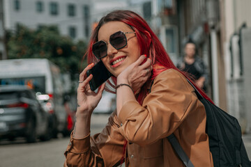 Obraz premium relaxed red-haired tourist woman with phone and backpack on the street