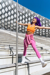 Carefree woman dancer wearing colorful sportswear having fun on the pole