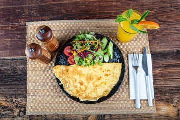 Photo of an omelet with cherry tomatoes, parsley. and grated cheese shot from above on a rustic wooden texture with a place for text. - obrazy, fototapety, plakaty