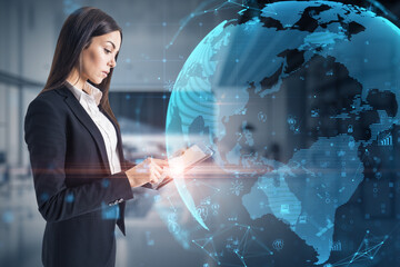 Attractive young caucasian businesswoman using tablet with glowing polygonal globe and social icons...