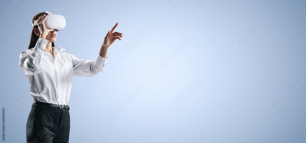 Poster young woman working in virtual reality environment in vr glasses, presses by her finger on virtual i