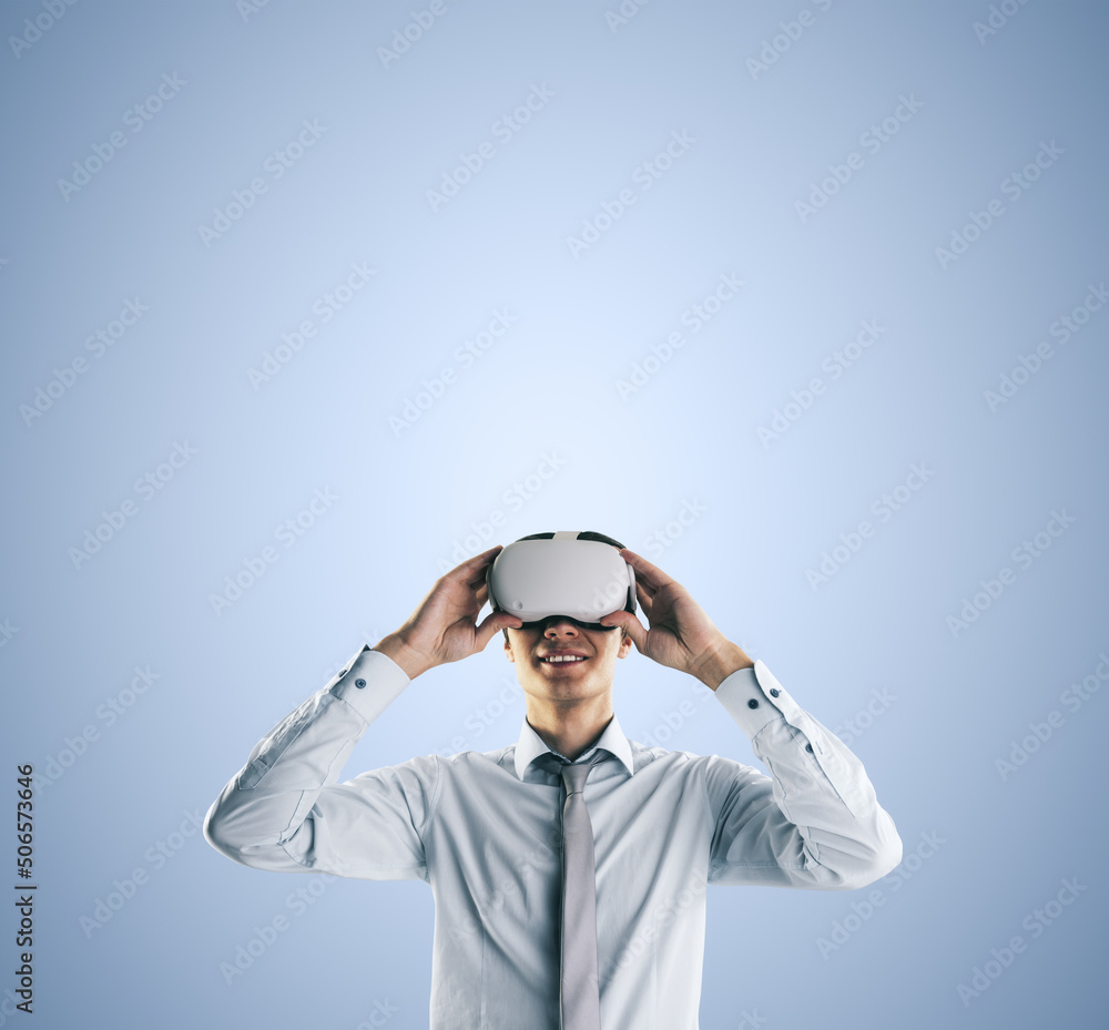 Poster virtual reality concept with young businessman gets new emotions in vr glasses on abstract light blu