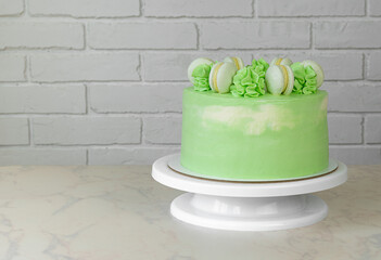 green cake on a stand with macaroons and cream