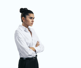 Resentment and unpleasant emotions concept with stressed young woman in white shirt crossing her arms isolated on light background, close up