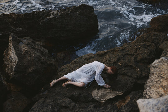 woman in a secluded spot on a wild rocky coast in a white dress unaltered