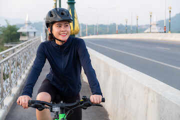 Young Asian cyclist woman exercise by riding a bicycle. Cycling is amazing for those looking for a...