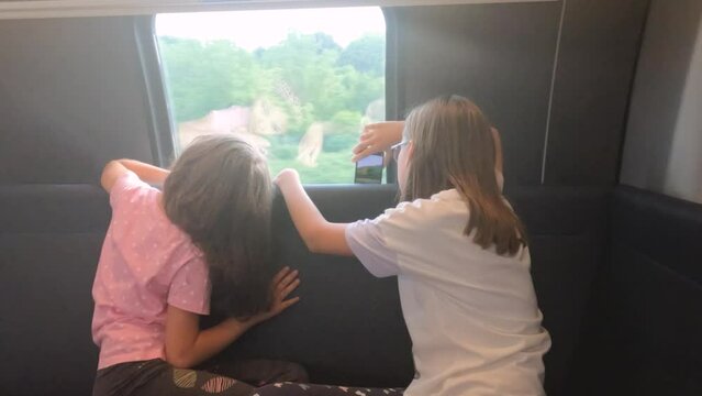 Children looking nature through motion train windows. Child taking photo with smartphone. Two little girls enjoy drive by train.