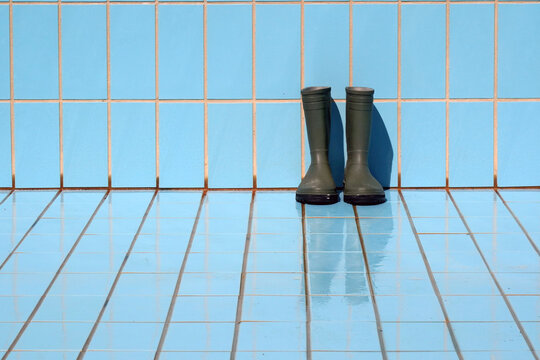 Regenstiefel stehen im leeren Pool an der Wand