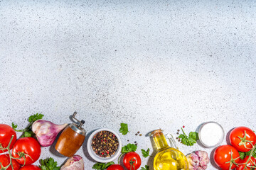 Cooking ingredients background. Spices, black pepper, garlic, onion, greens, tomatoes. olive oil on white stone concrete table top view copy space. Preparation healthy food background.