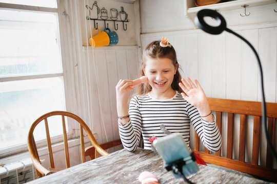 Preteen girl in kitchen shoots video with cosmetics, video blogger and streamer