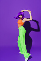 Carefree woman dancer wearing colorful sportswear performing against purple background