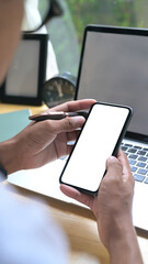 Close up over shoulder view of young man using mobile phone in home office