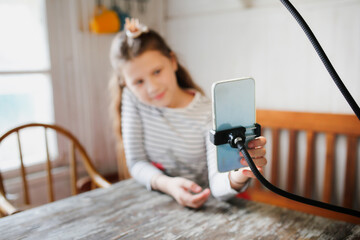 Preteen girl in kitchen shoots video with cosmetics, video blogger and streamer