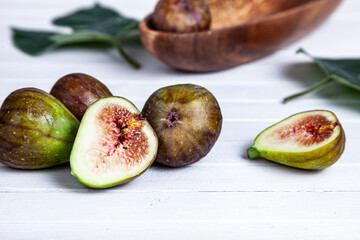 Figs and leaves on a white wooden background.