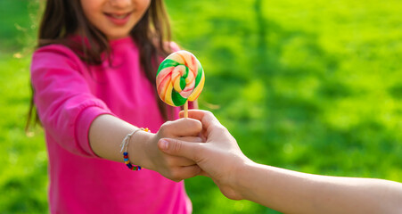 A child eats a lollipop in the park. Selective focus.