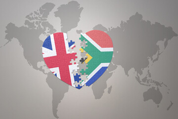 puzzle heart with the national flag of south africa and great britain on a world map background....