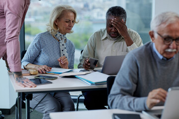 Multicultural senior students in a classroom looking at the phone and asking hard questions about social media.