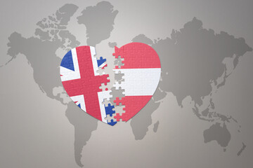 puzzle heart with the national flag of austria and great britain on a world map background. Concept.