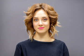 Portrait of a beautiful young caucasian red-haired woman with short wavy hairstyle smiling and...