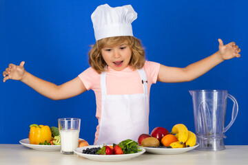 Excited funny chef cook. Fruits and vegetables for kids. Portrait of chef child in cook hat. Cooking at home, kid boy preparing food from vegetable and fruits. Healthy eating.