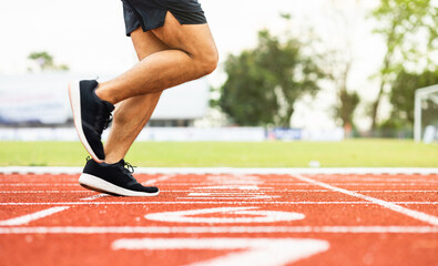 Close up legs Young chinese man wearing sportswear running on track at sport stadium. Fit man jogging outdoor cross the finish line. Exercise in the morning. Healthy and active lifestyle concept.