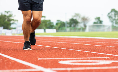 Close up legs Young chinese man wearing sportswear running on track at sport stadium. Fit man...