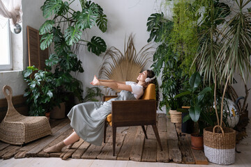 Relaxed calm woman rest in home garden breathing fresh air, listen music. Happy gardener girl enjoy...