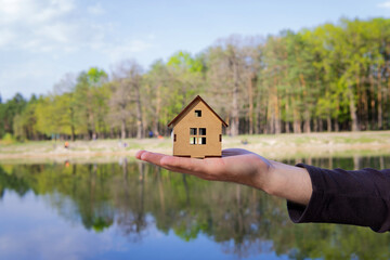 House model in hand against lake background