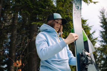 Portrait of an attractive girl in the mountains in a blue hoodie and cap who wears a camus on skis and is going to climb the mountains on skis