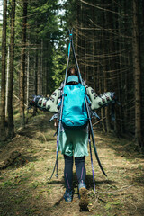 Girl skier goes through the spring forest in search of snow. Girl with a backpack and skis in the mountains walks in the woods