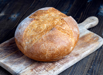 a whole loaf of bread on a cutting wooden board