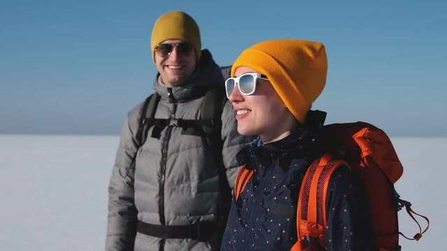 The two travelers with backpacks walk through the snow field. slow motion