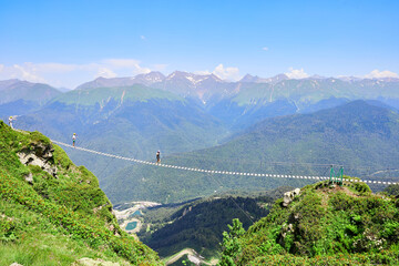 People walk on a suspension bridge in the mountains