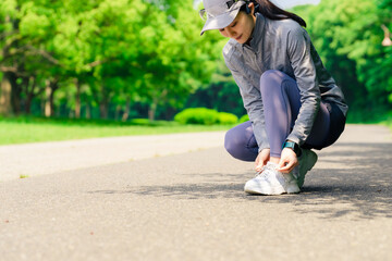 トレーニング前に靴紐を結ぶ女性　運動　ジョギング