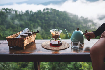 Closeup image of a woman making drip coffee with a beautiful mountain and nature view in background