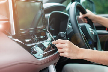 Woman hand adjusting temperature the air flowing during driving car on the road, air conditioner cooling system inside the car. Adjust, temperature and transport concept