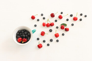 Top view image of colorful assorted mix of berries, blueberry and sweet cherry over wooden white background