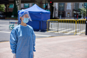 Medical worker in protective suits and surgical face masks on the street. City blockade. - obrazy, fototapety, plakaty