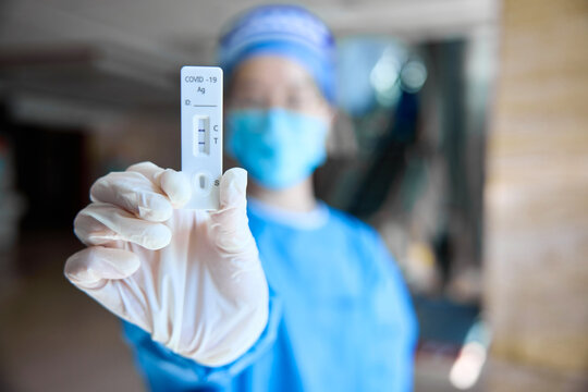 Doctor in medical suit showing a positive antigen test result for the new rapidly spreading Coronavirus Covid-19.